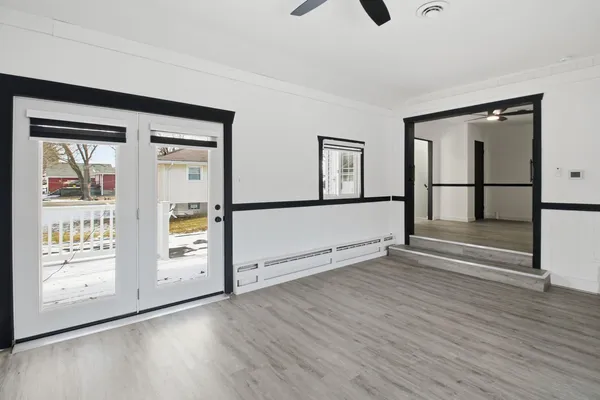 a view of an empty room with window and wooden floor