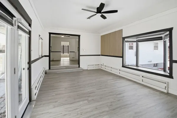 a view of empty room with wooden floor and fan