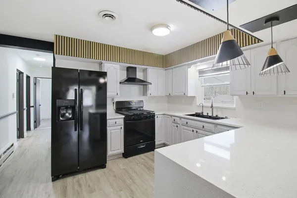 a kitchen with stainless steel appliances granite countertop a refrigerator a sink dishwasher a stove and white cabinets