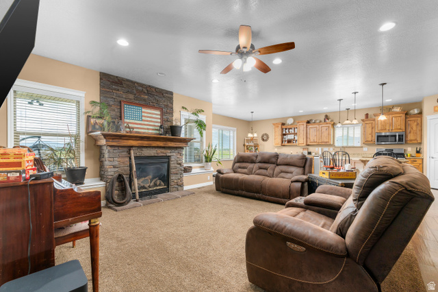 5702 950 North Ogden, UT 84404 - Photo 13 of 36 Living area featuring a stone-faced fireplace with a wood mantle, recessed lighting, and a ceiling fan