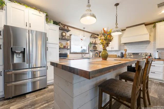 a kitchen with granite countertop a refrigerator and a stove top oven