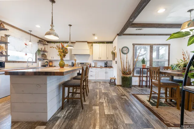 a kitchen with stainless steel appliances granite countertop a table chairs stove and a wooden floor