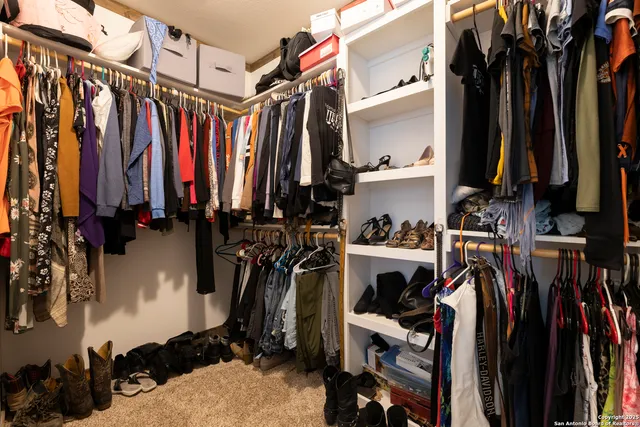 a view of walk in closet with clothes and shoes