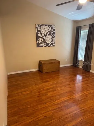 a view of an empty room with wooden floor and a window