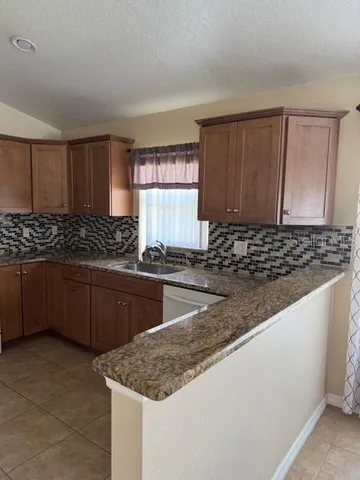 a kitchen with granite countertop a sink a stove and cabinets