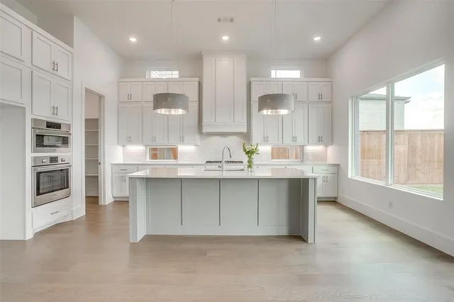 a open kitchen with kitchen island a sink dishwasher a stove and a refrigerator with wooden floor