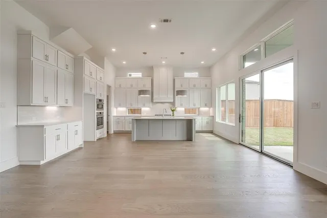 a large white kitchen with a large window and stainless steel appliances