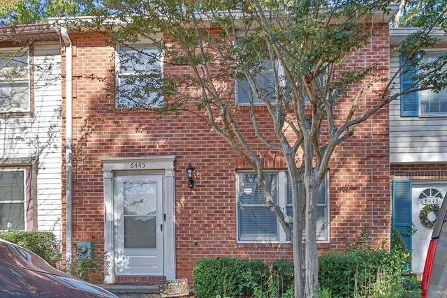a front view of a house with a tree