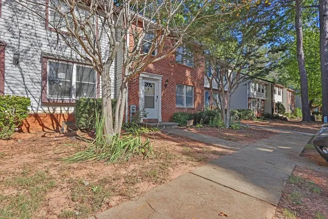 a tree in front of a brick house with a large tree