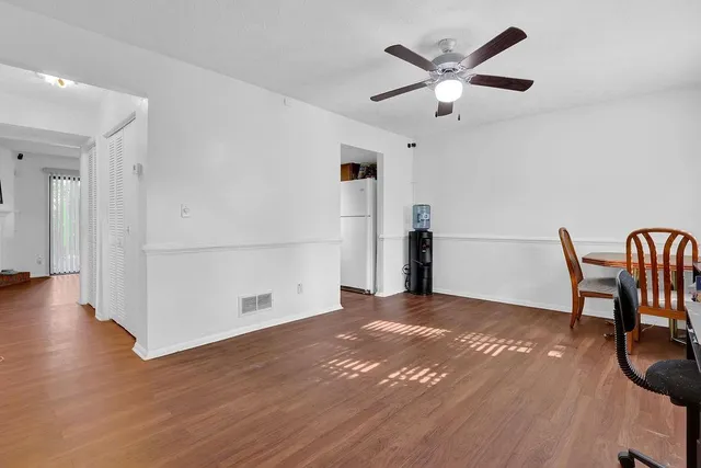 a view of a livingroom with a dinning area hardwood floor and a ceiling fan