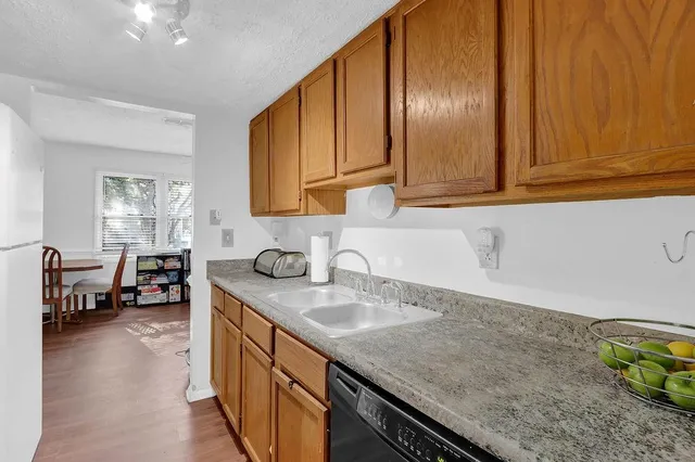 a kitchen with stainless steel appliances granite countertop a sink dishwasher stove and cabinets with wooden floor