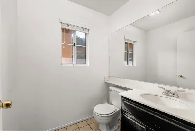a bathroom with a granite countertop toilet sink and mirror