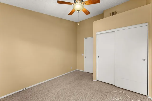 an empty room with a ceiling fan and carpet