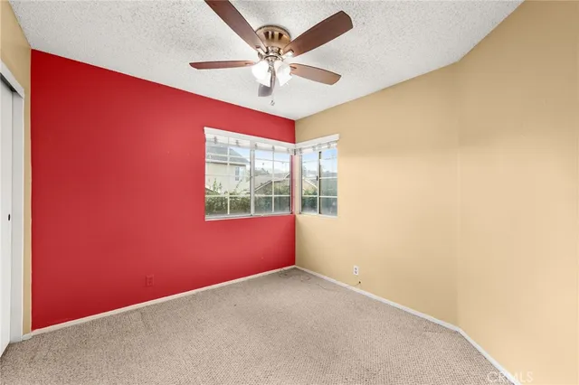 an empty room with windows and fan