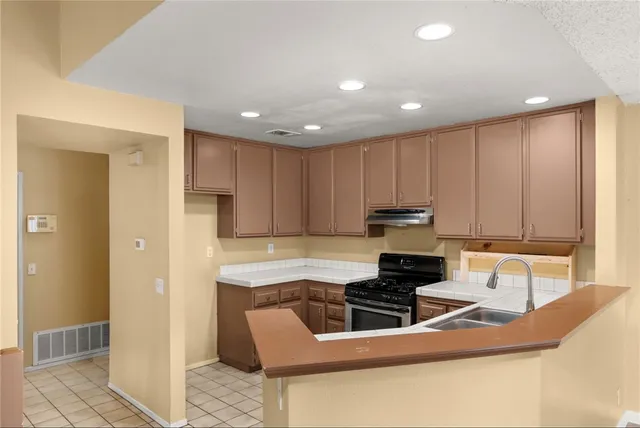 a kitchen with kitchen island granite countertop stainless steel appliances stove refrigerator and cabinets