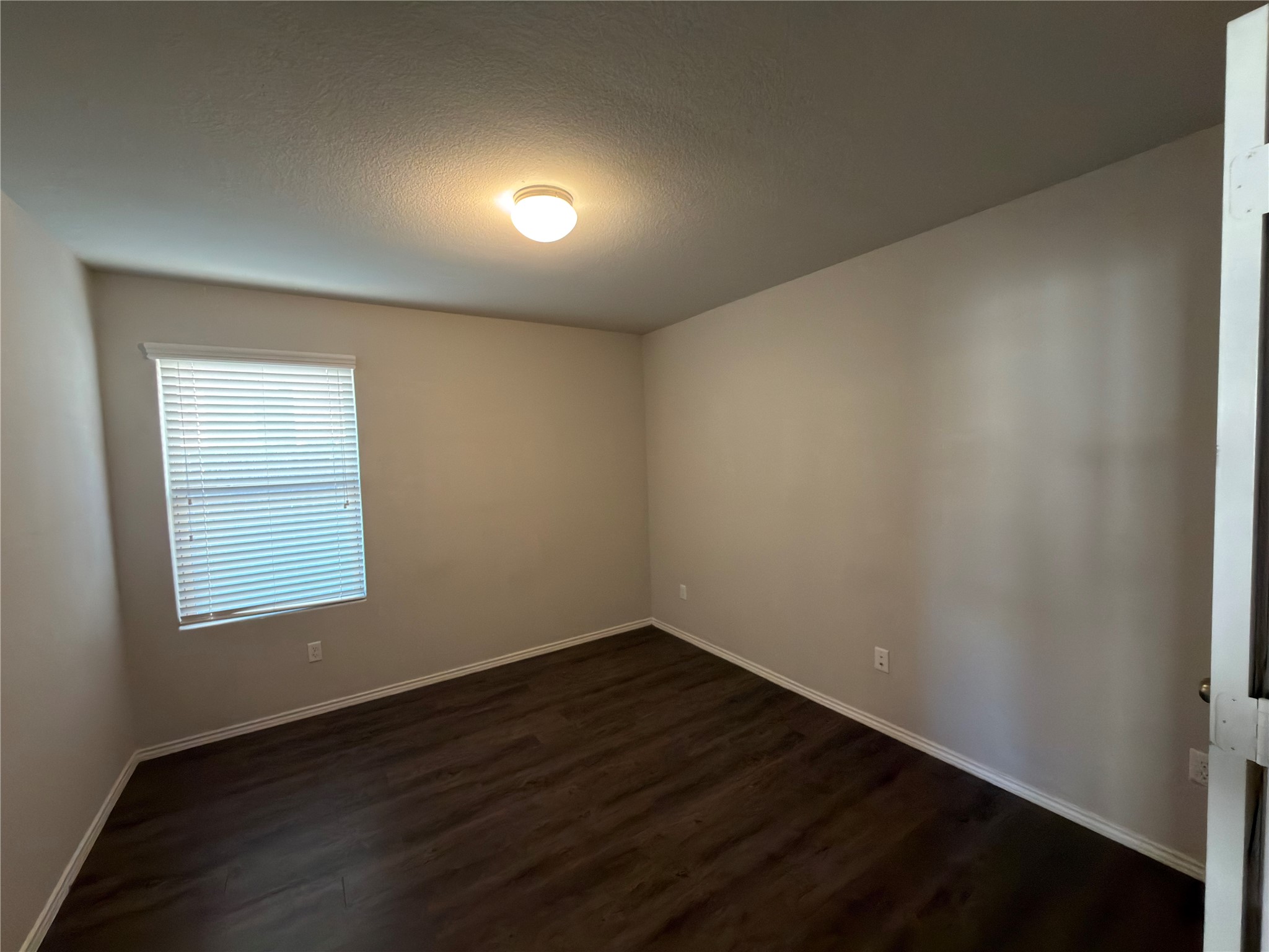 21700 Urraca Lane Pflugerville, TX 78660 - Photo 12 of 40 Empty room featuring a textured ceiling and dark wood-style floors