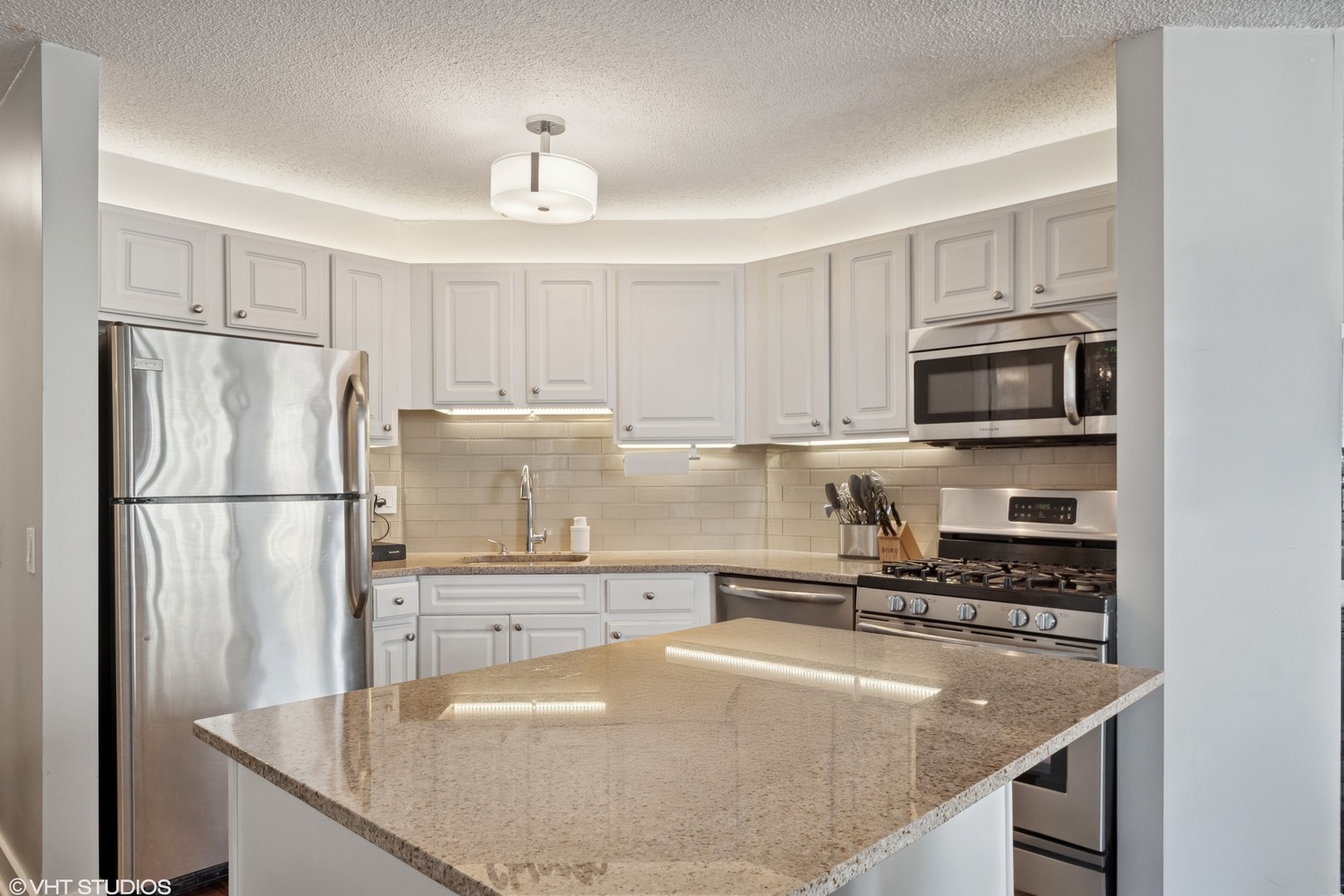 545 North Dearborn Street, Unit 1904 Chicago, IL 60654 - Photo 9 of 35 a kitchen with kitchen island granite countertop a sink stove and refrigerator