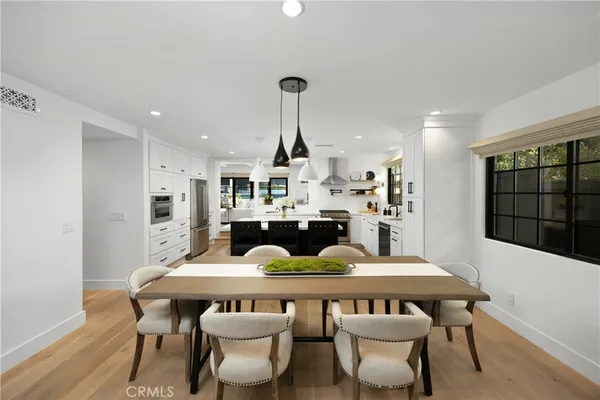 a large kitchen with stainless steel appliances a stove a sink dishwasher and a refrigerator with wooden floor