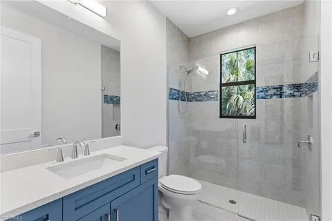a bathroom with a granite countertop sink a mirror a toilet and shower