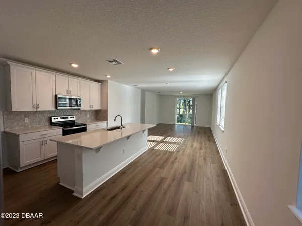 a kitchen with granite countertop a stove top oven a sink dishwasher and a refrigerator with wooden floor