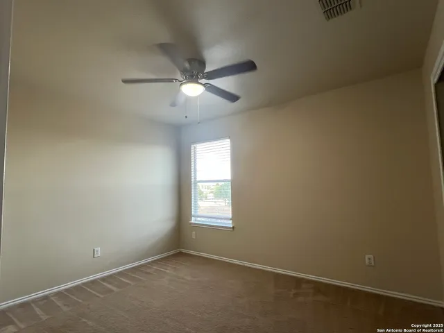 an empty room with a window and a fan