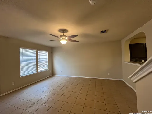 a view of an empty room with window and chandelier fan