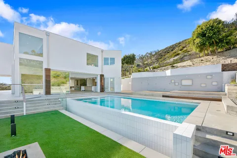 a large white kitchen with stainless steel appliances kitchen island a large counter top and a refrigerator