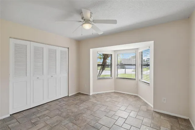a view of a big room with wooden floor a ceiling fan and windows