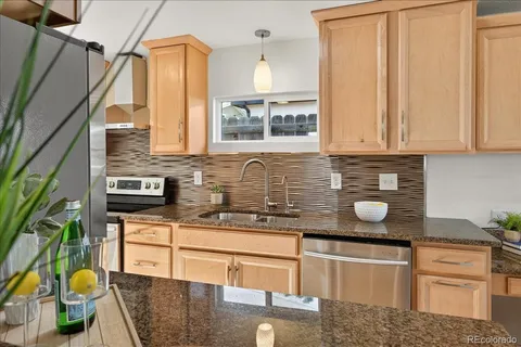 a kitchen with stainless steel appliances granite countertop a sink a stove and cabinets