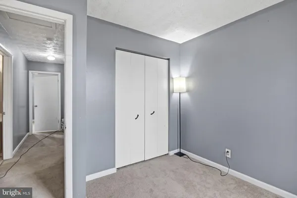 a view of an empty room with closet and a mirror