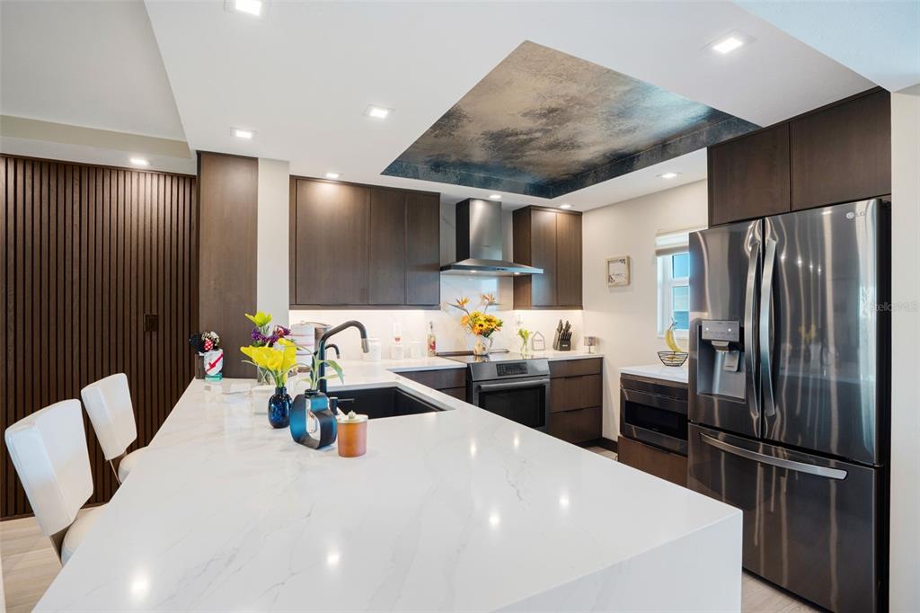9397 Midnight Pass Road, Unit 905 Sarasota, FL 34242 - Photo 3 of 37 a kitchen with stainless steel appliances a refrigerator sink and wooden floor