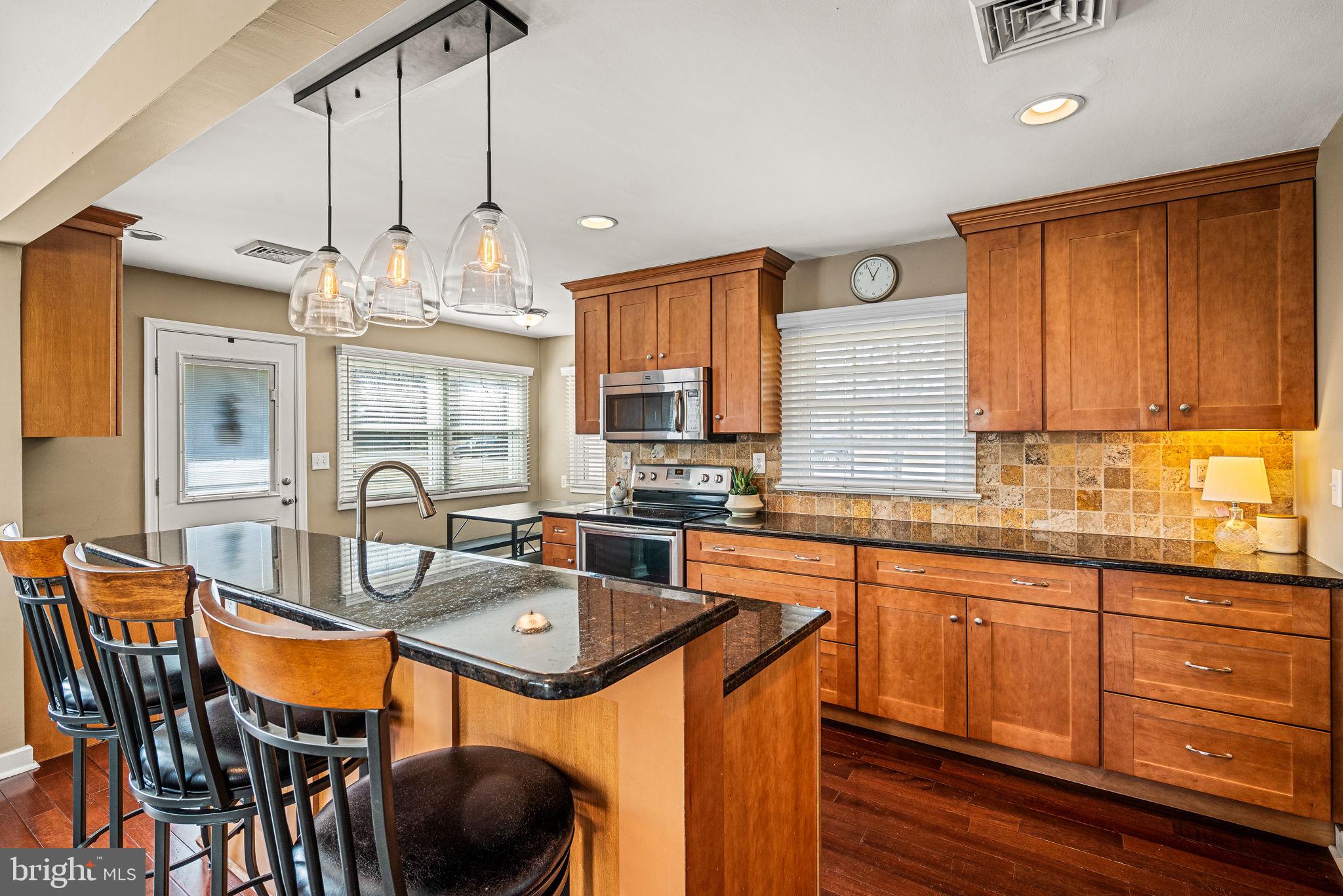 408 Scott Lane Wallingford, PA 19086 - Photo 12 of 39 a kitchen with stainless steel appliances granite countertop a stove a sink dishwasher a dining table and chairs with wooden floor