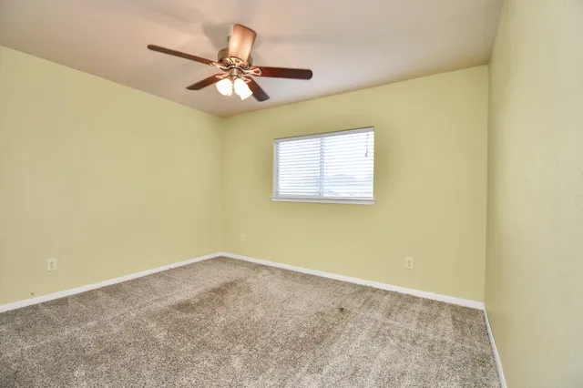 an empty room with a window and ceiling fan