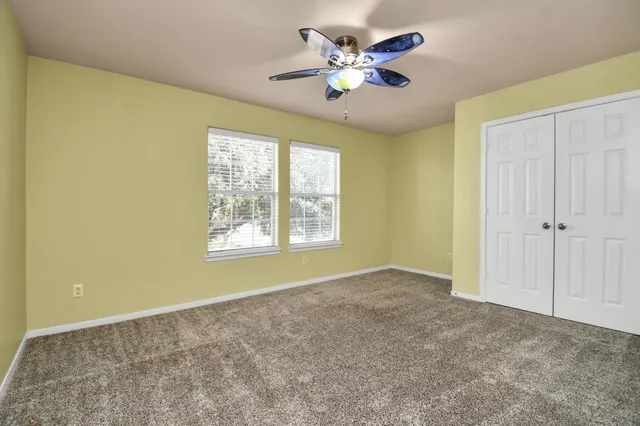 an empty room with windows and chandelier fan