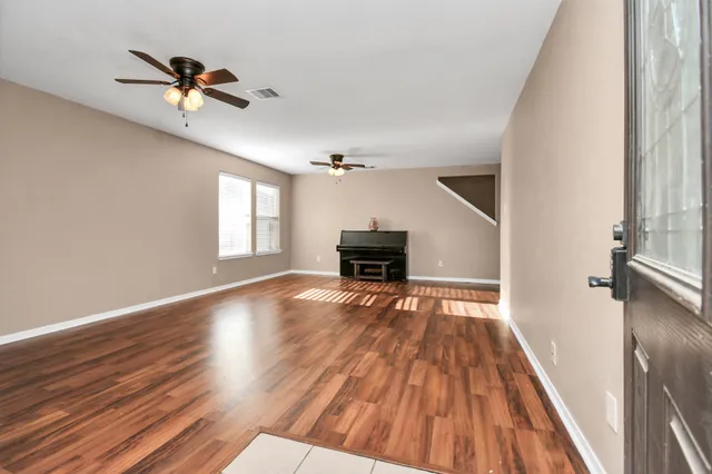 a view of an empty room with wooden floor and a window