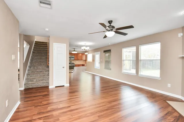 a view of an empty room with wooden floor and a window