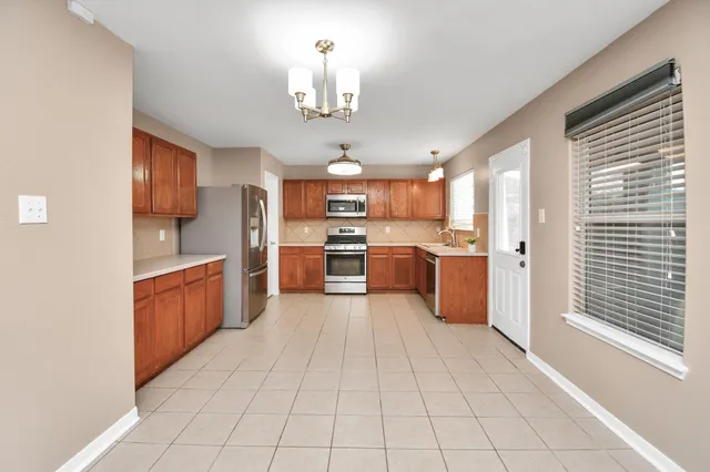 a large kitchen with stainless steel appliances granite countertop a stove a sink dishwasher and a refrigerator with wooden floor