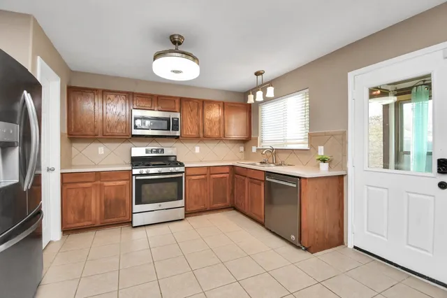 a kitchen with stainless steel appliances granite countertop a stove top oven a sink and a refrigerator