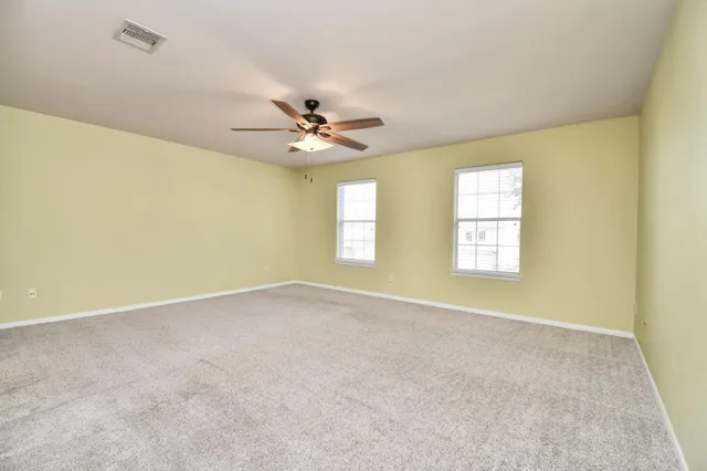 an empty room with windows and fan