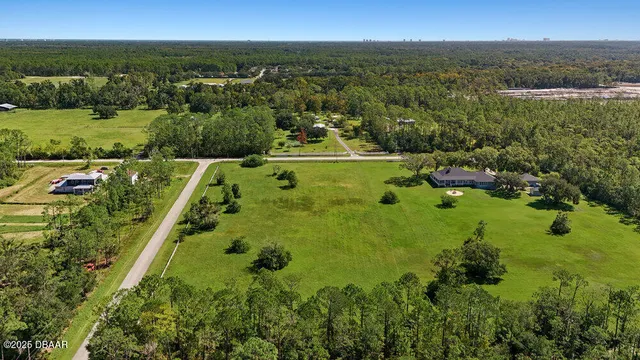 an aerial view of residential houses with outdoor space and trees