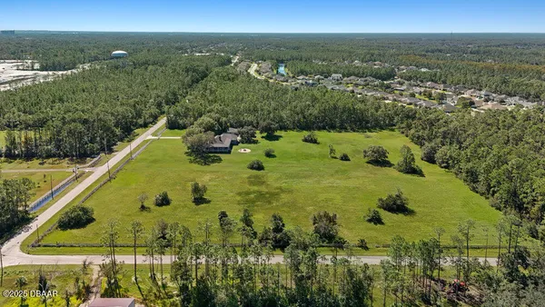 an aerial view of residential houses with outdoor space and trees