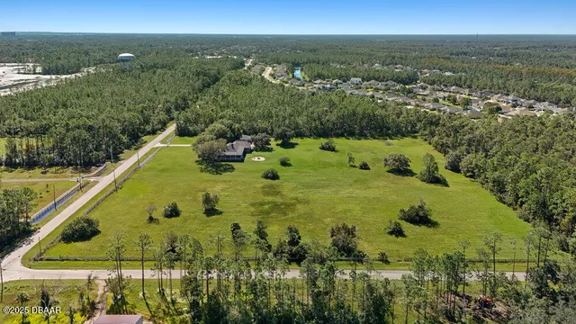 an aerial view of residential houses with outdoor space and trees