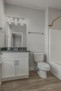a bathroom with a granite countertop toilet a sink and a mirror