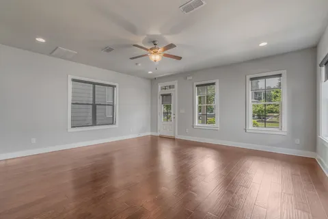 a view of an empty room with a window and wooden floor