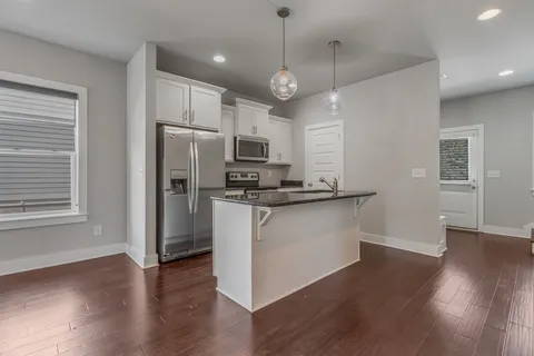 a kitchen with granite countertop a refrigerator a stove a microwave and wooden floor