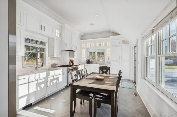 a kitchen with stainless steel appliances granite countertop a stove a sink a refrigerator and white cabinets with wooden floor