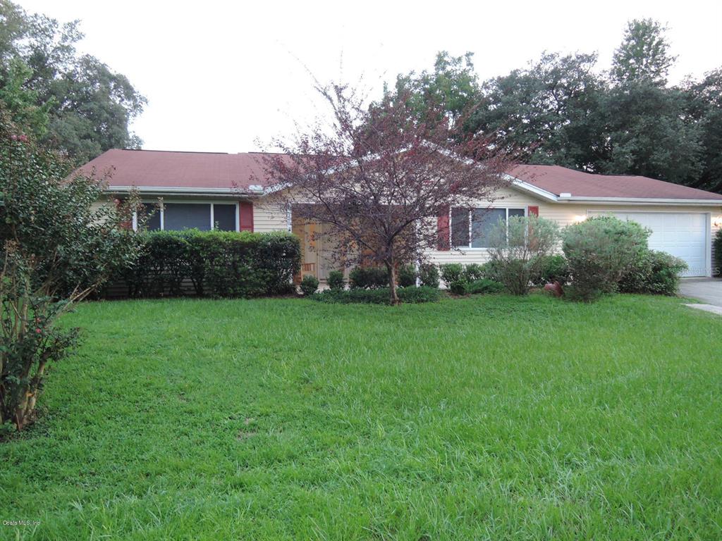 a front view of a house with garden and trees