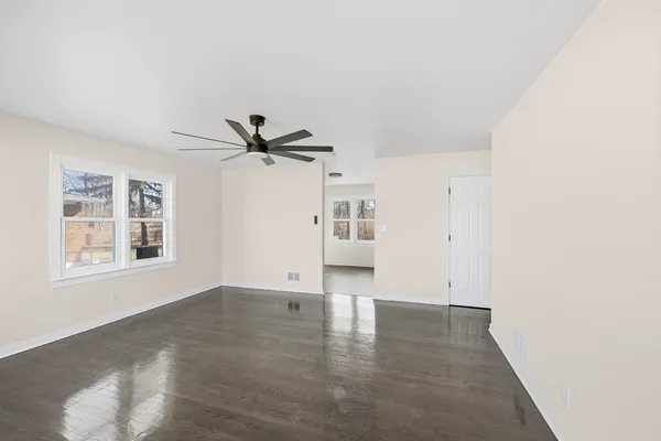 a view of empty room with wooden floor and windows
