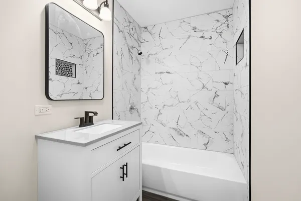 a bathroom with a bathtub sink vanity and mirror