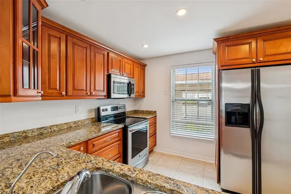 a kitchen with stainless steel appliances granite countertop a refrigerator a stove and a sink with wooden floor